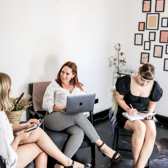 Three women in an office, one has a laptop on her lap and they're talking about Digital Marketing Agency Sunshine Coast